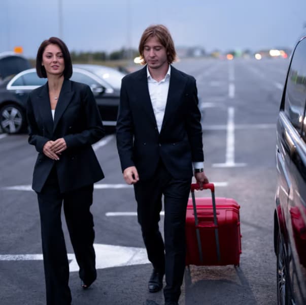 Couple with luggage walking to a black car — Chicago airport transfers